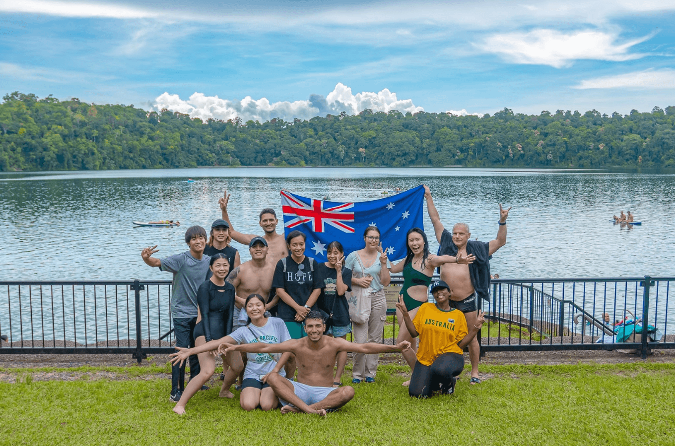 澳洲語言學校推薦：SPC (Sun Pacific College) 學生在風景優美的凱恩斯湖畔戶外活動中與澳洲國旗開心合照，透過豐富的課外探索建立自信與外國人交流。